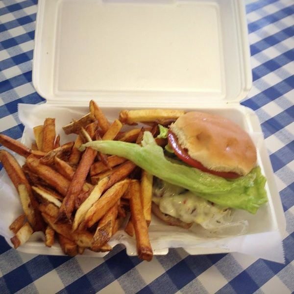 Cheeseburger with lettuce and tomato beside a pile of fresh cut fries