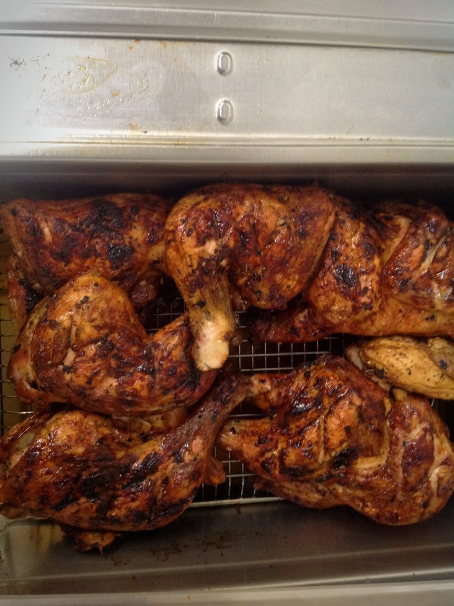 Giant BBQ chicken leg quarters resting in the warmer