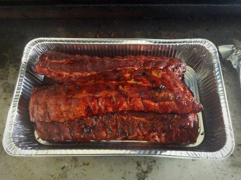 Racks of baby back ribs glazed with barbecue sauce in a pan